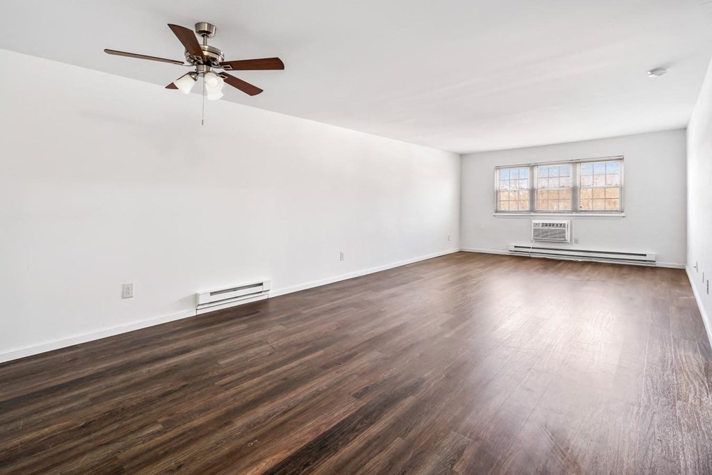 an empty living room with wood floors and a ceiling fan