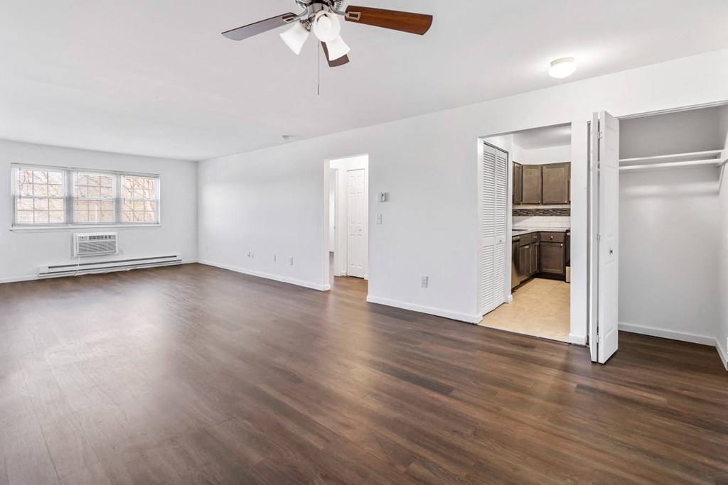 an empty living room with wood floors and a ceiling fan