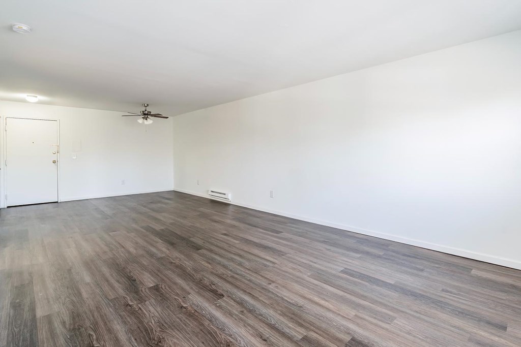 an empty living room with white walls and wood floors