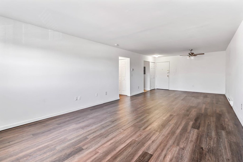 an empty living room with wood flooring and a ceiling fan