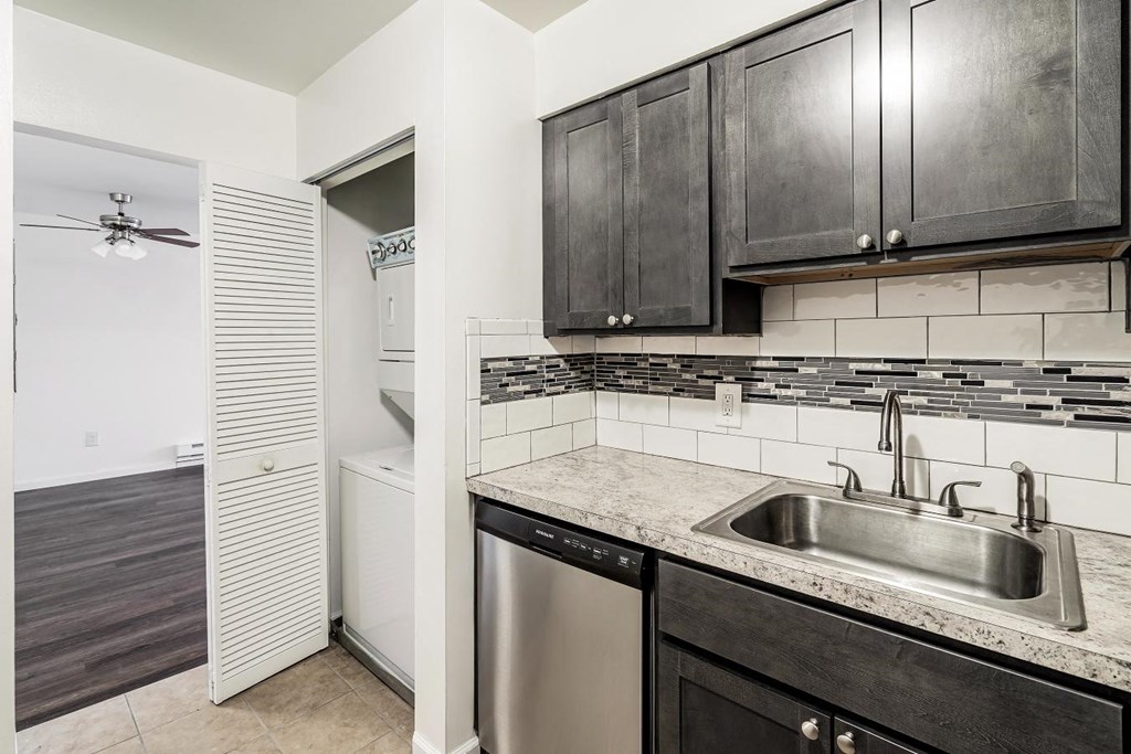 a kitchen with black cabinets and a stainless steel sink
