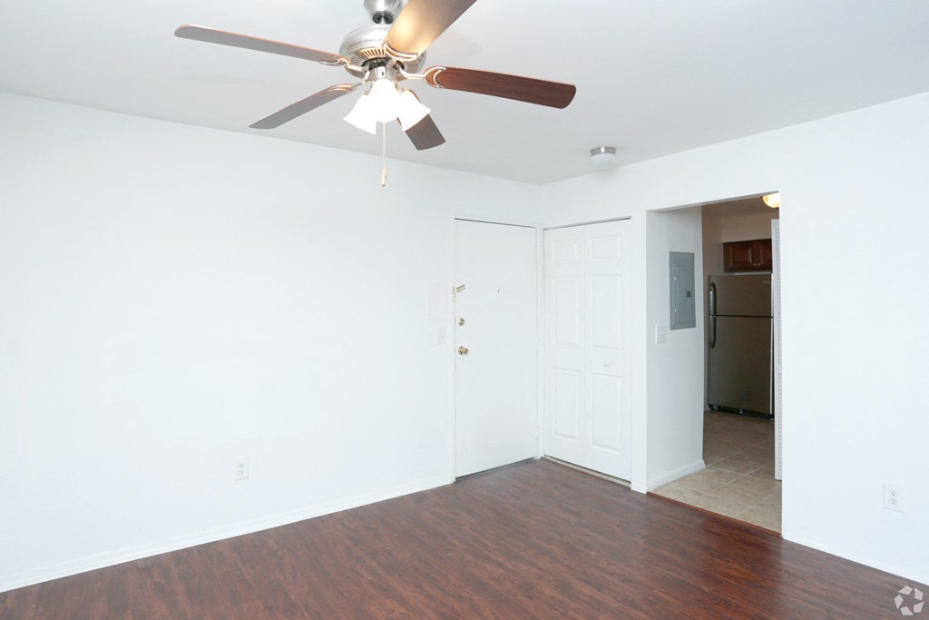an empty living room with a ceiling fan