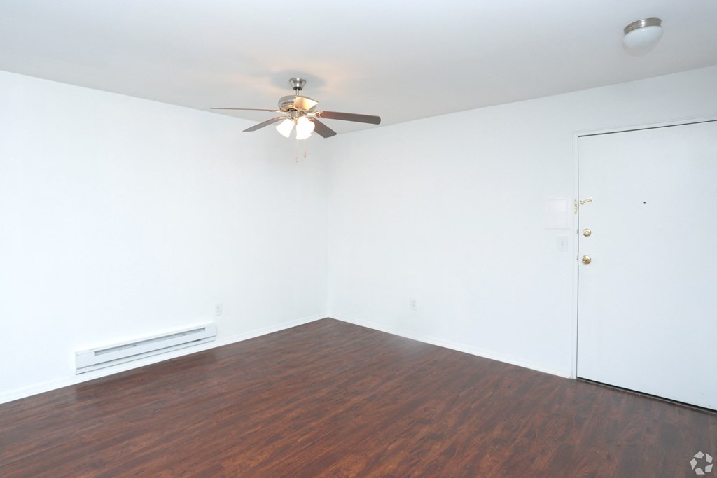 an empty living room with wood floors and a ceiling fan