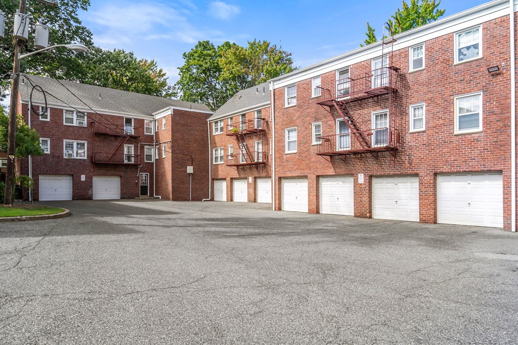 an empty parking lot in front of a brick apartment building