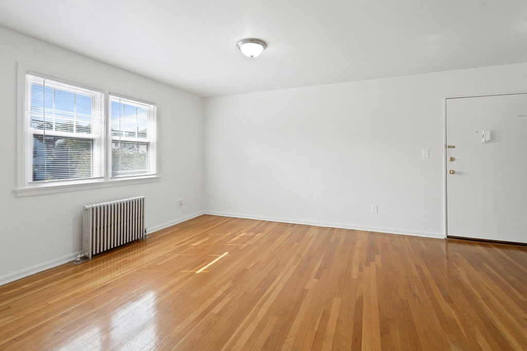 an empty living room with wood flooring and a window
