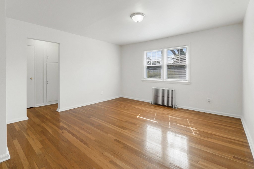 an empty living room with wood floors and a window