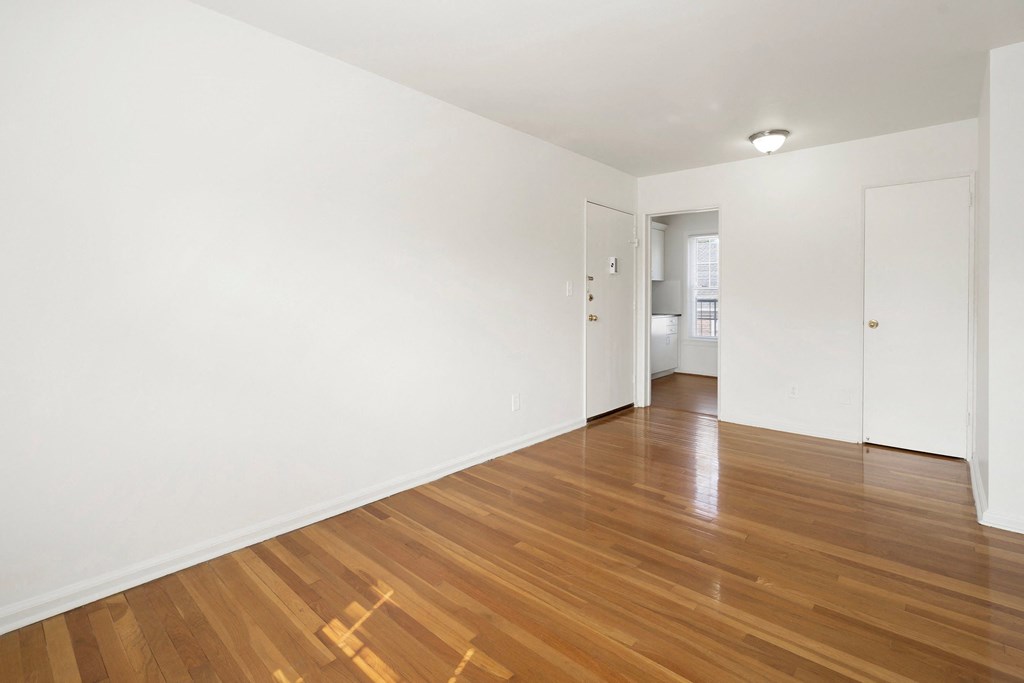 an empty living room with white walls and wood floors