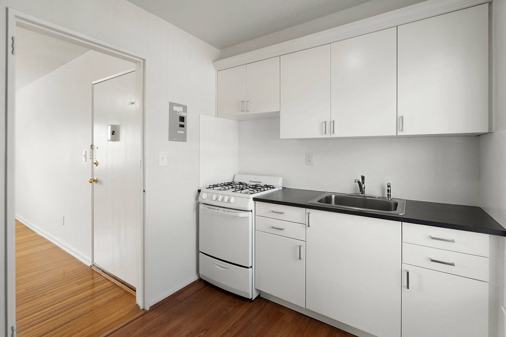 an empty kitchen with white cabinets and a stove and a sink