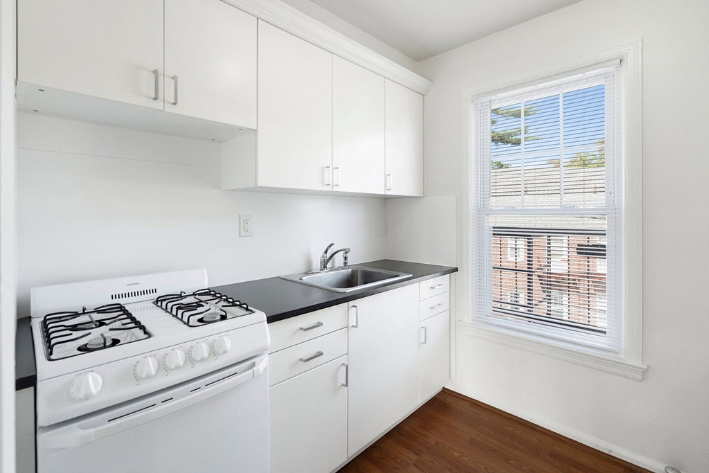 an empty kitchen with white appliances and a window