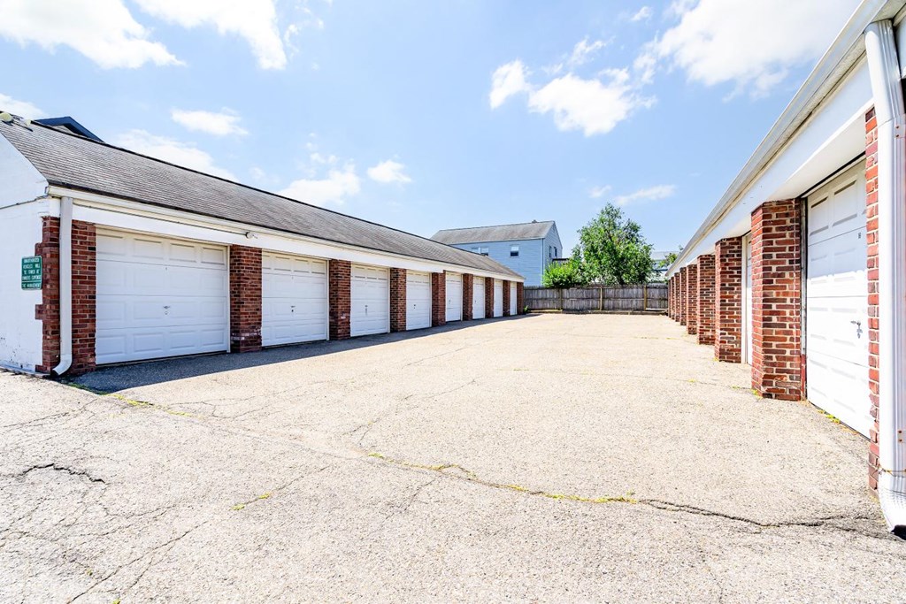 a long row of garages with white doors and brick columns