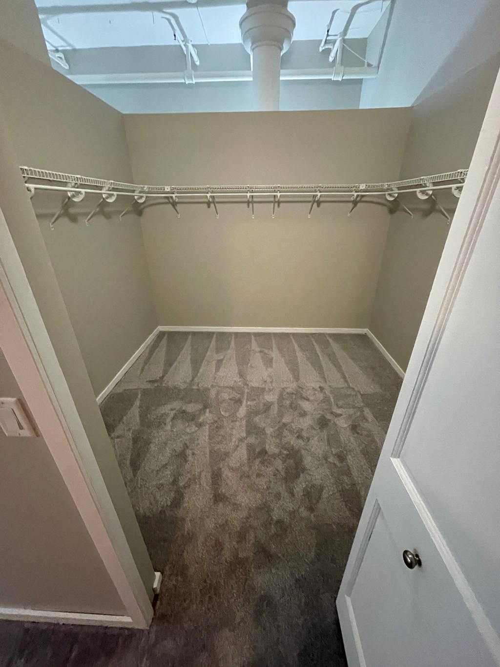 a empty closet with a carpeted floor and a white closet door