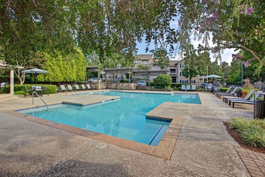 a swimming pool with trees and chairs around it