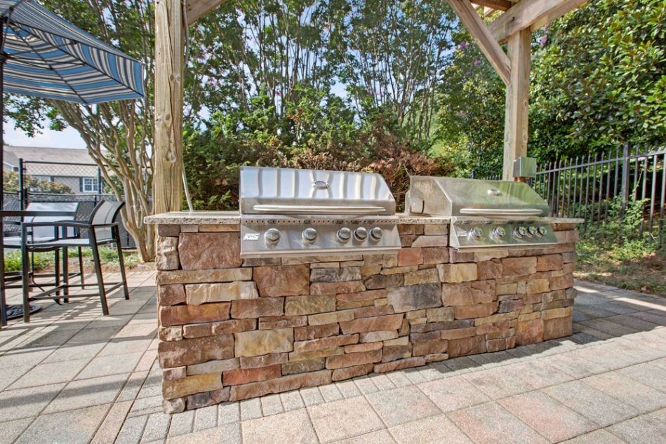 a large outdoor kitchen with a grill on a patio