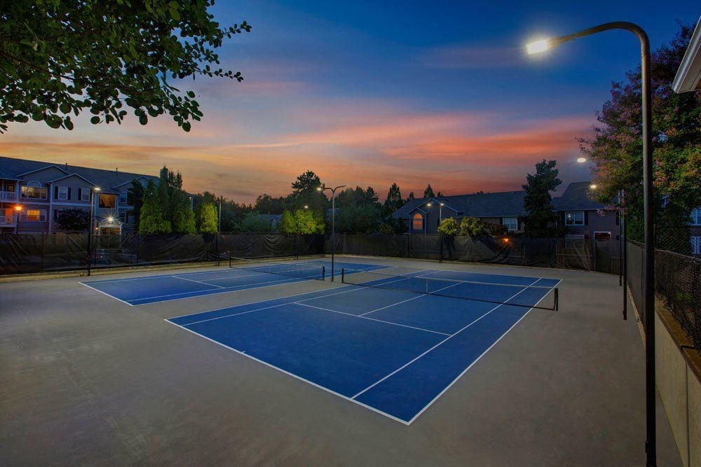 a blue tennis court with a sunset in the background