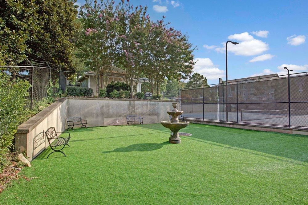 the backyard is fenced in with a lawn and a fountain