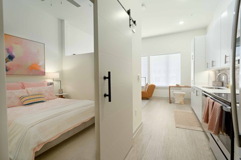A bedroom with a bed and a kitchen area in the same room.