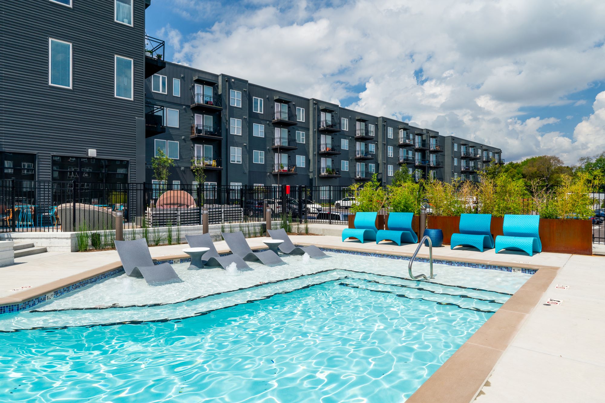 A swimming pool with lounge chairs in front of a building.