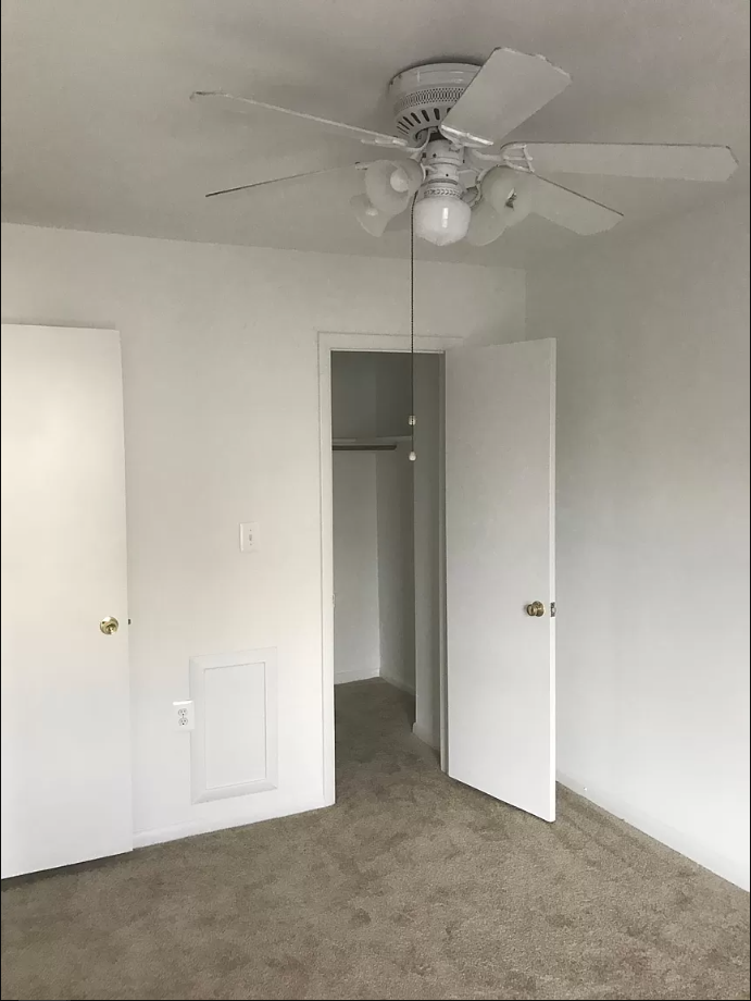 an empty bedroom with a ceiling fan and a closet