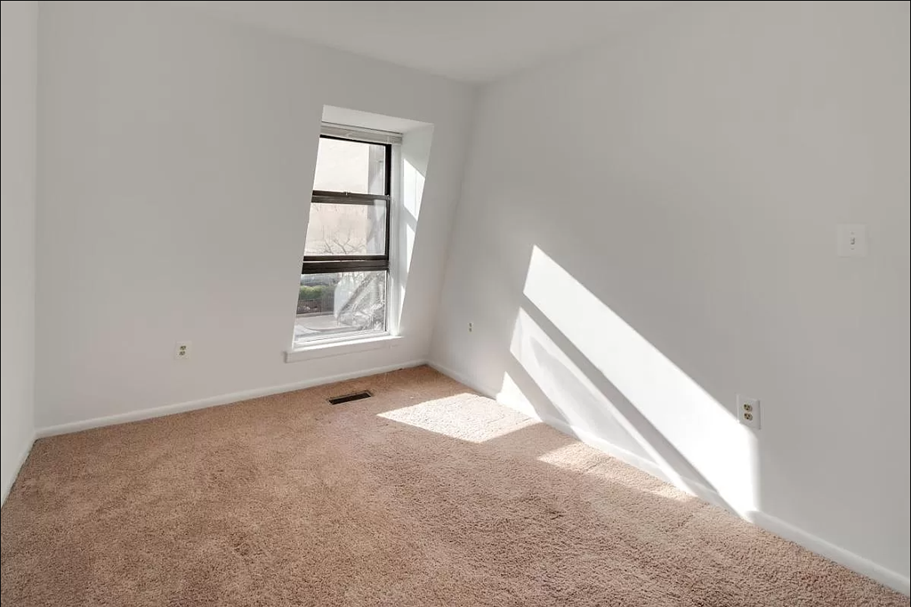 an empty room with a window and carpet