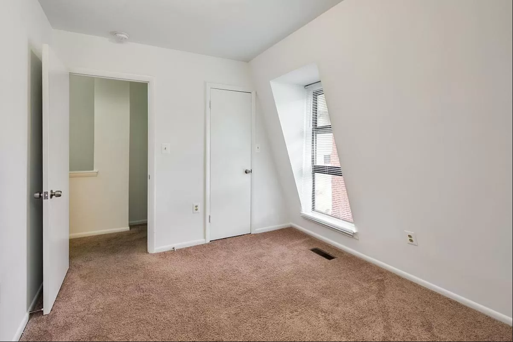 an empty bedroom with a window and a closet