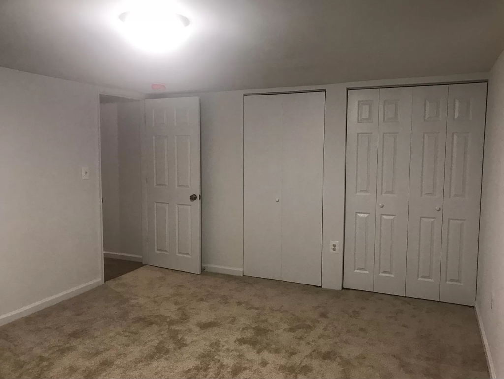 a bedroom with three closets and a carpeted floor