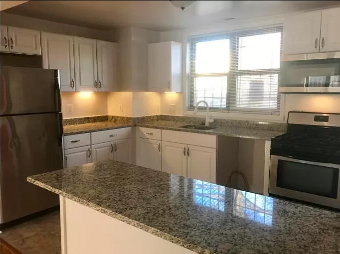 a kitchen with granite counter tops and white cabinets