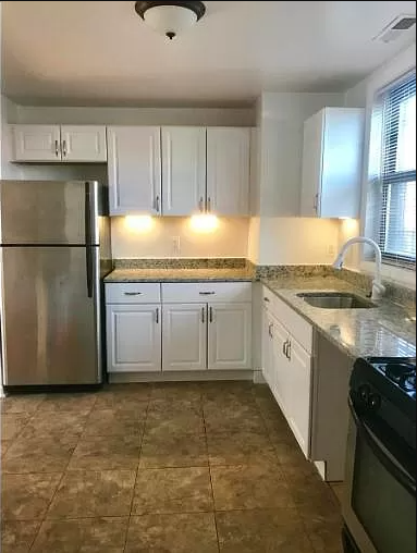 a kitchen with white cabinets and a stainless steel refrigerator