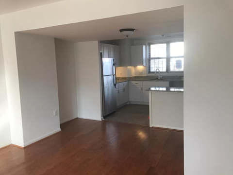 an empty living room and kitchen with a wooden floor