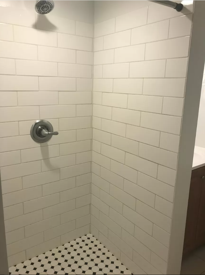 a small white tiled shower in a bathroom
