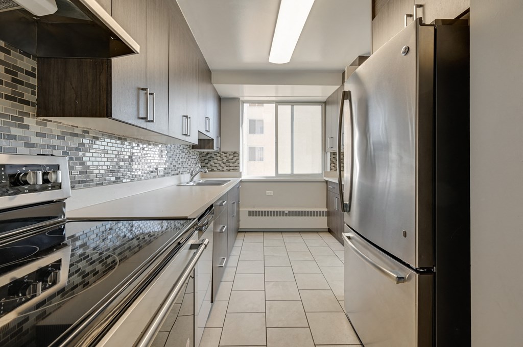 a kitchen with white countertops and a stainless steel refrigerator