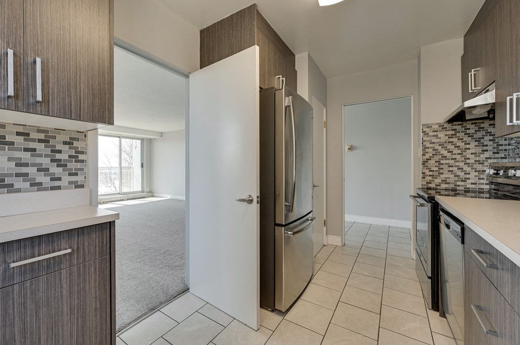 a kitchen with a refrigerator and a door to a living room