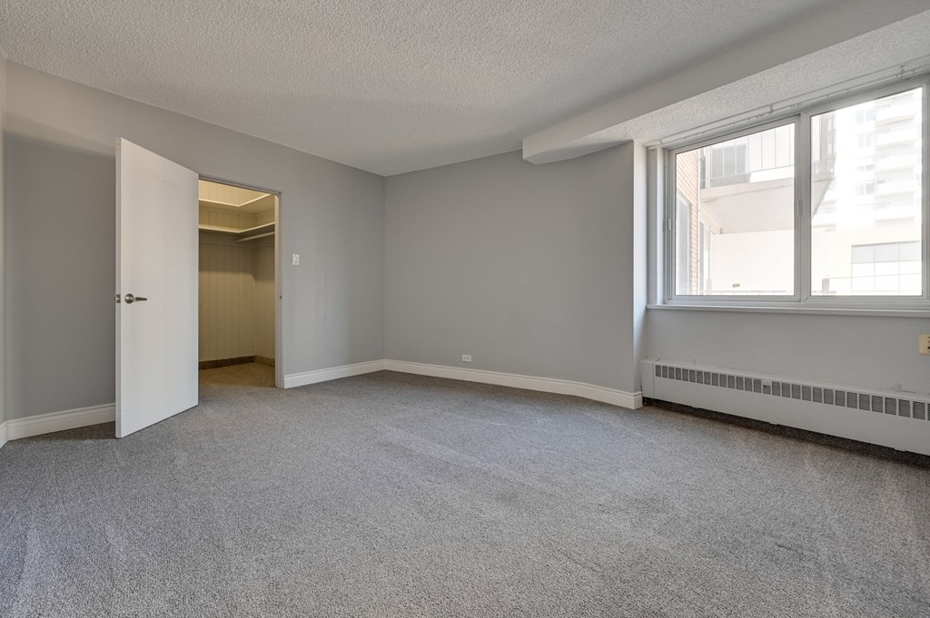 an empty living room with two windows and a door to a hallway
