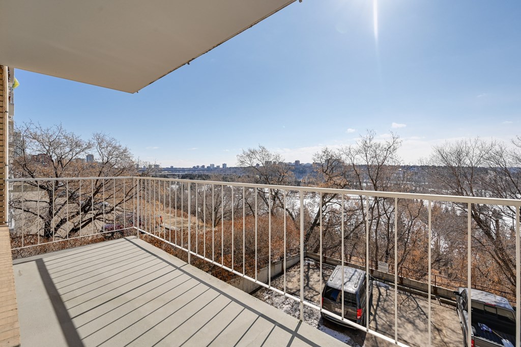 the view from the balcony of a condo with a parking lot and trees