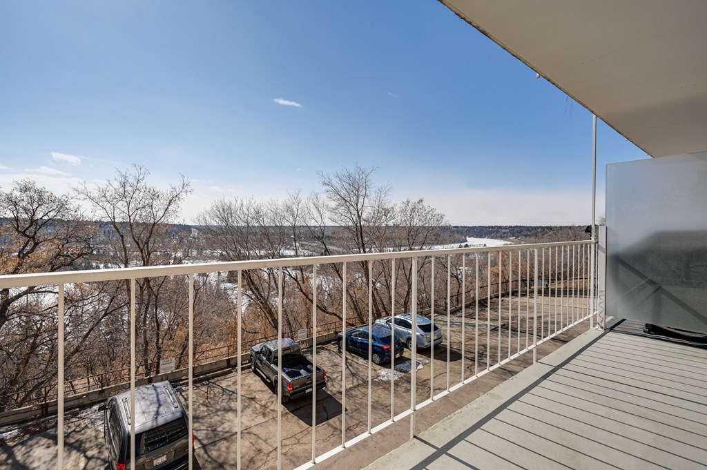 a balcony with a view of a parking lot and some trees