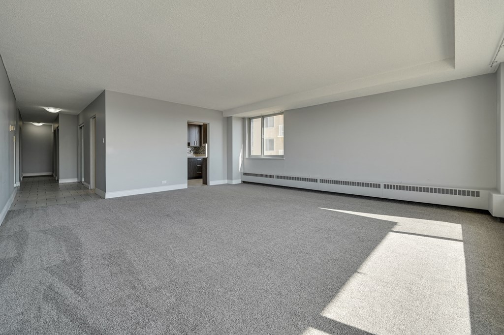 the spacious living room and dining room in a new home with white walls and carpet