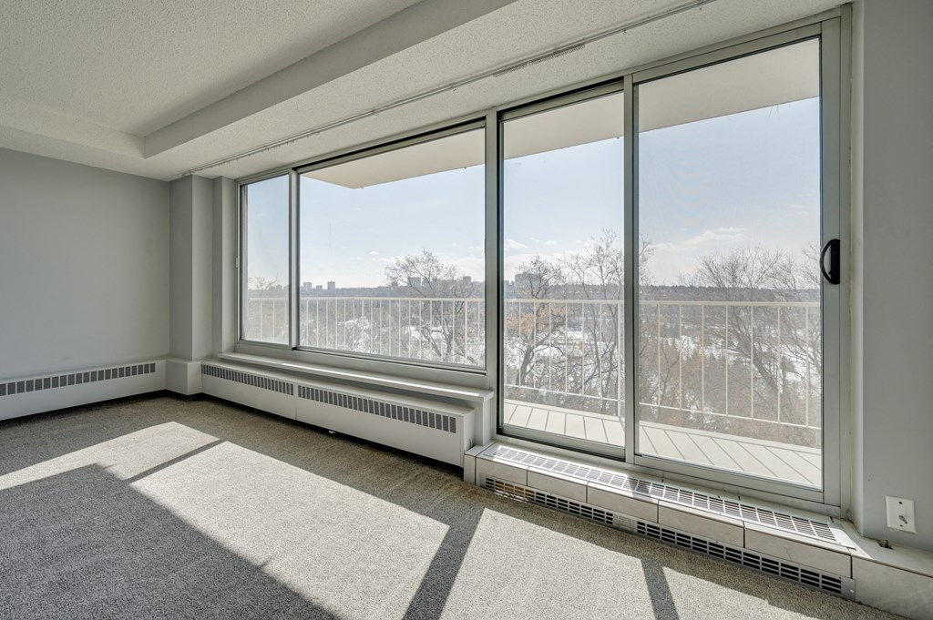 an empty living room with large windows and a view of a field