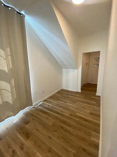 A room with wooden flooring and a door on the right side.