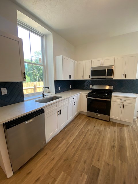 A kitchen with wooden floors and white cabinets.