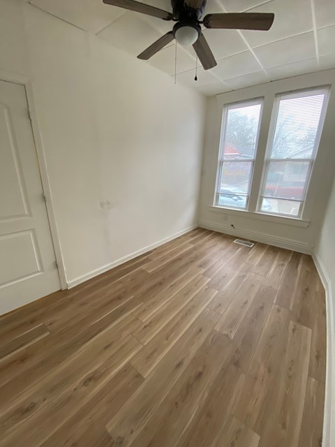 A room with a ceiling fan and wooden flooring.