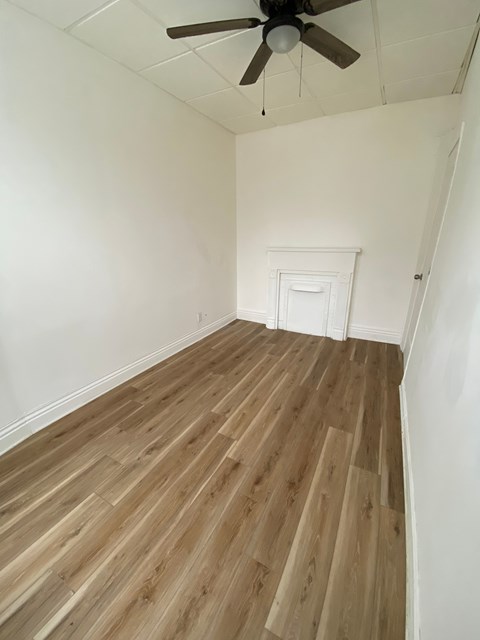 A room with wooden flooring and a ceiling fan.