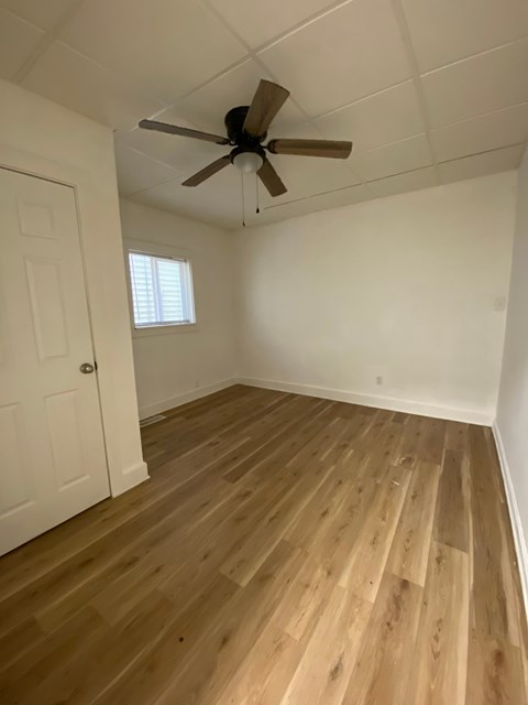 A room with a ceiling fan and wooden flooring.