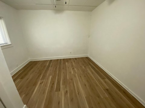 A room with wooden flooring and white walls.