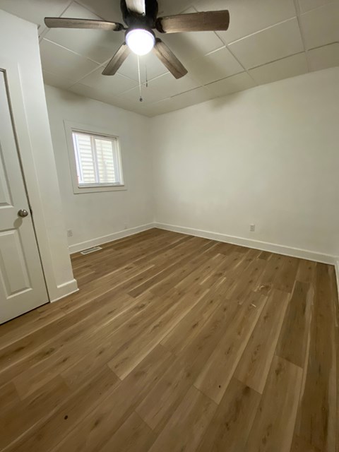 A room with a ceiling fan and wooden flooring.