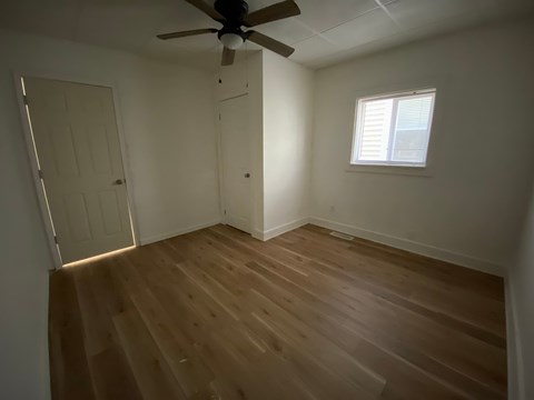 A room with a ceiling fan and wooden flooring.