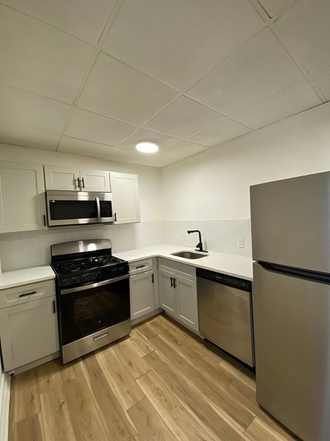A kitchen with a stove, sink, and refrigerator.