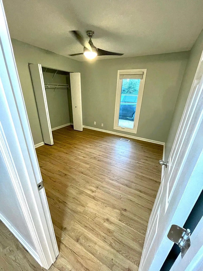 a empty room with wooden floors and a ceiling fan