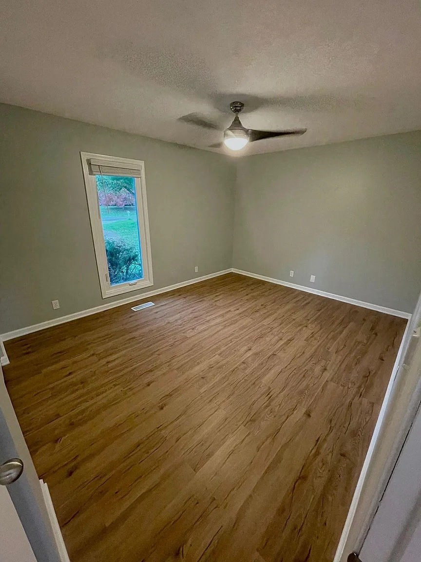 a empty room with a wood floor and a ceiling fan