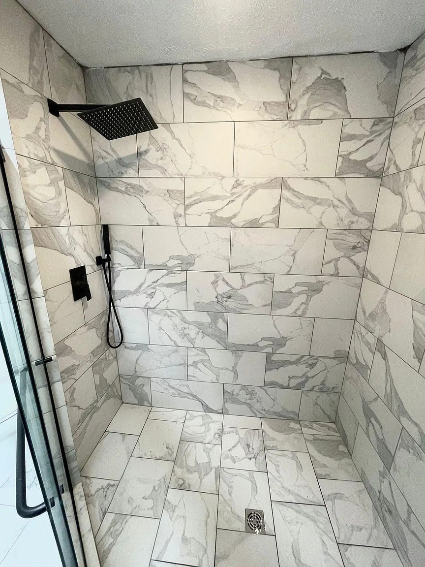 a large shower with marble tile in a shower stall with a shower head