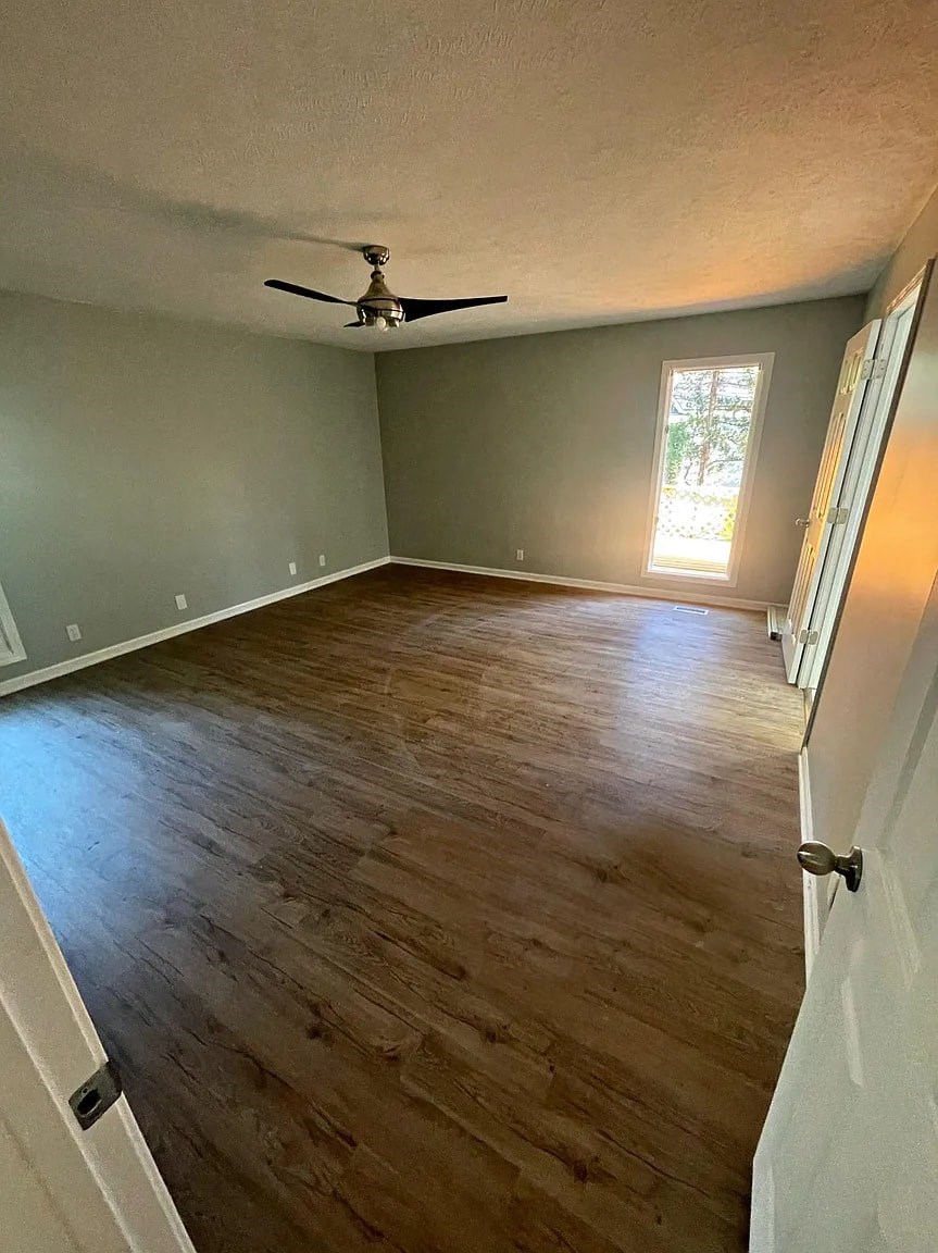 a empty living room with a ceiling fan and wood floors