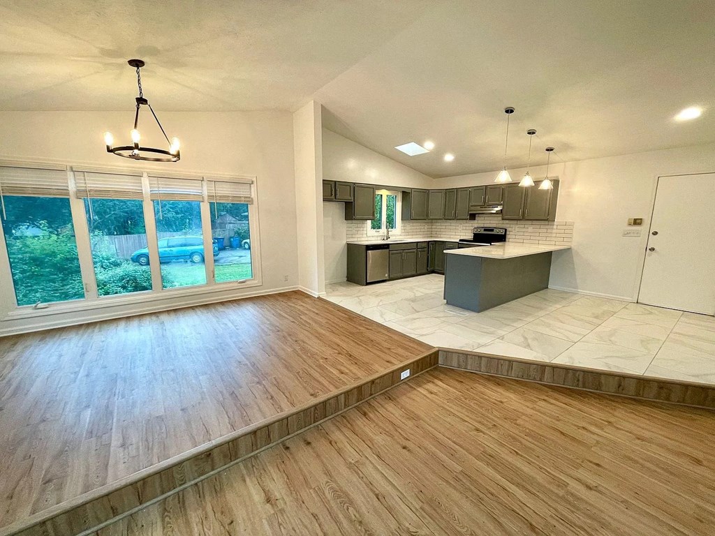 an empty living room and kitchen with a large window